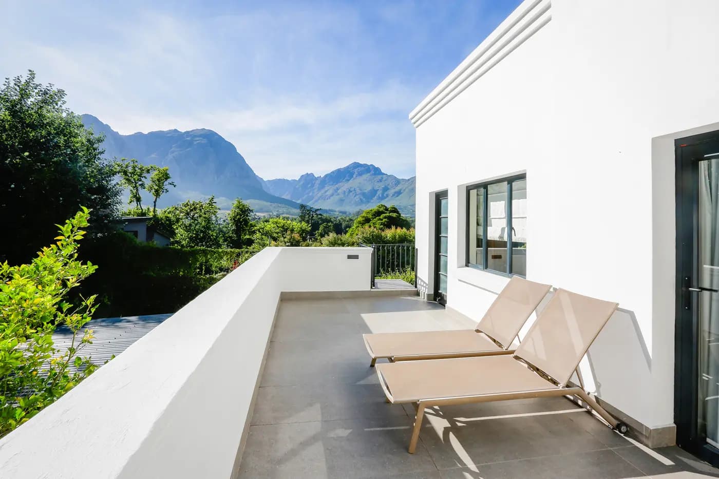 Sun loungers on a terrace looking out over vineyards and mountains