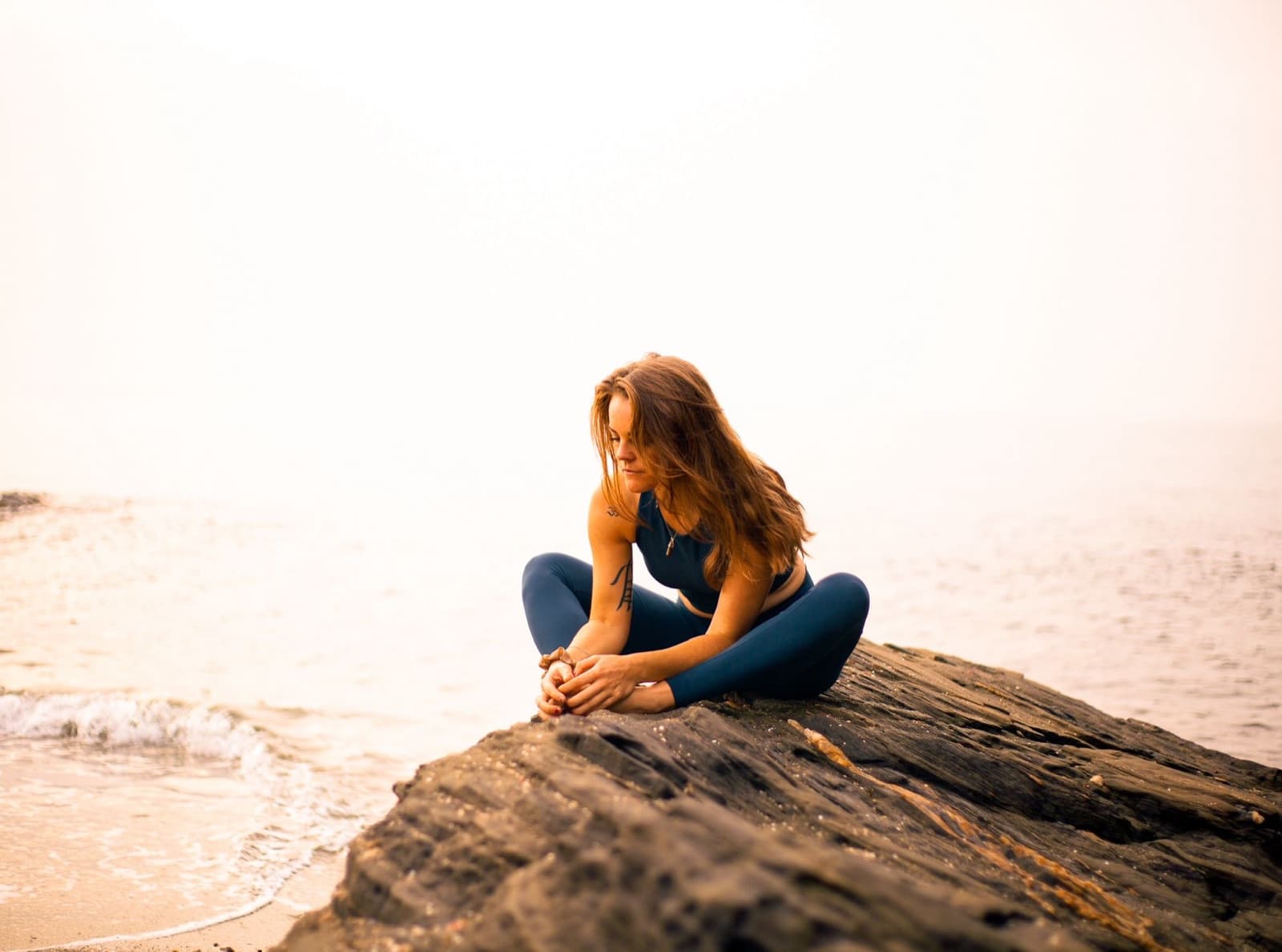 Seána in a seated bound-angle pose by the sea